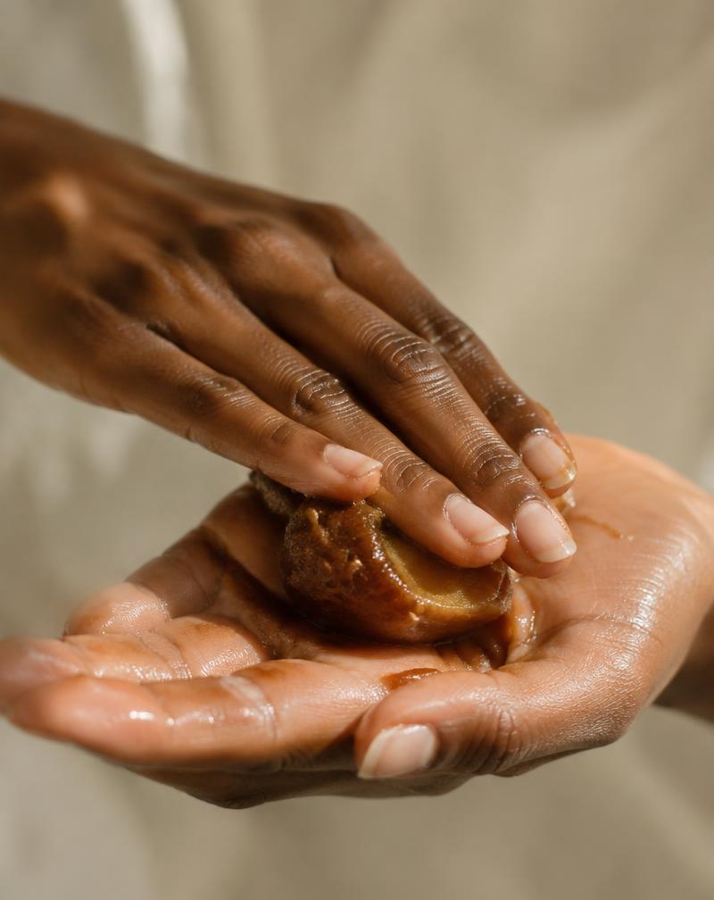Batana oil balm warmed between palms and in its amber jar